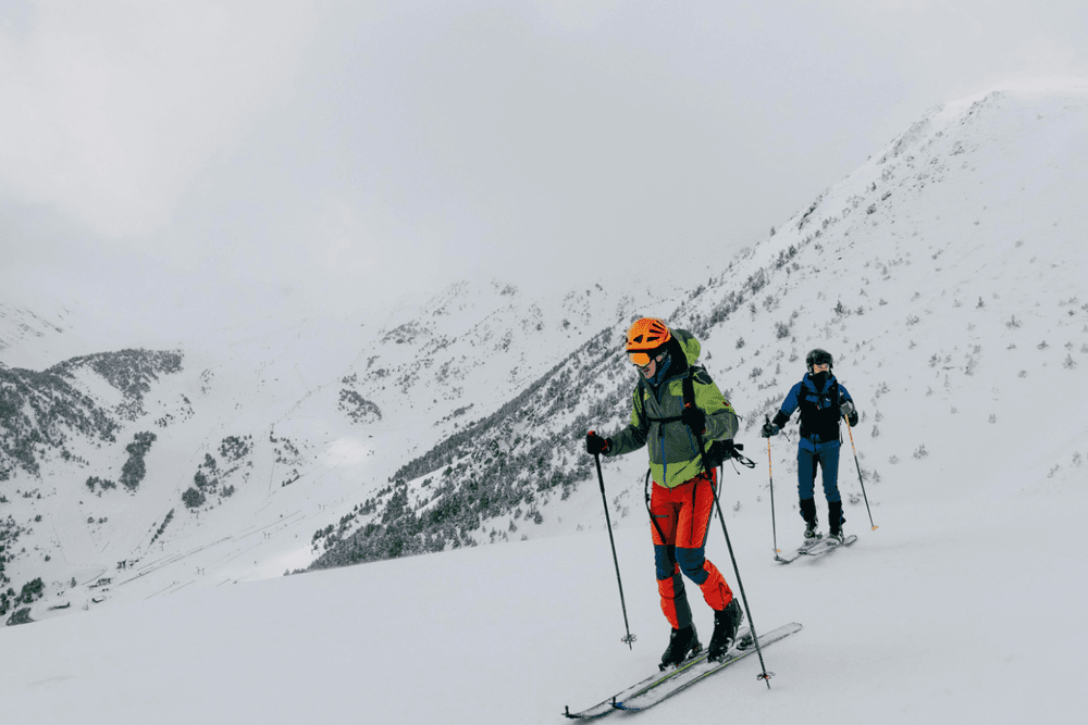 Two skiers navigating a snowy mountain landscape.