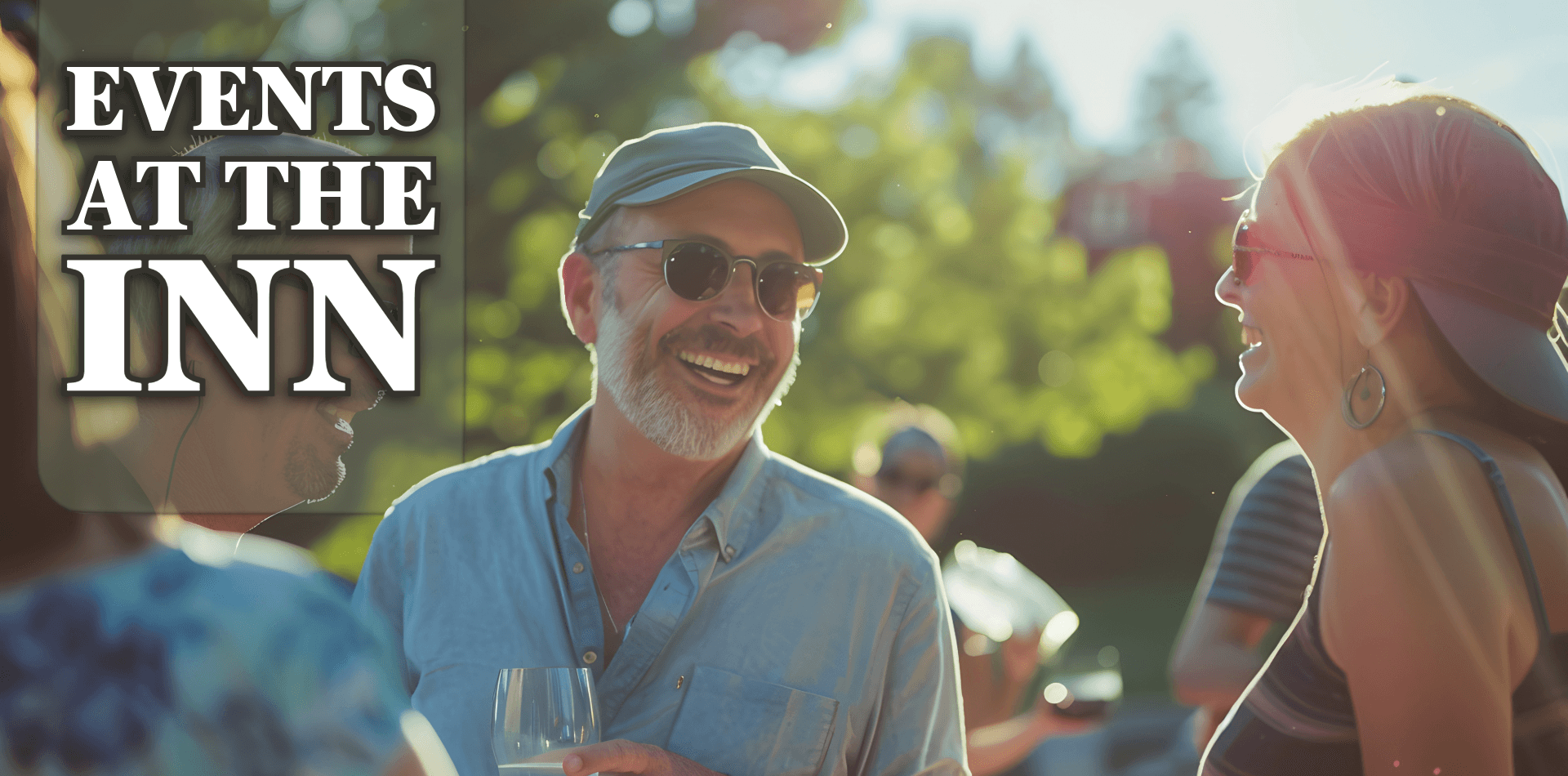 A smiling man in sunglasses enjoys a conversation with a woman at an outdoor event near an inn.