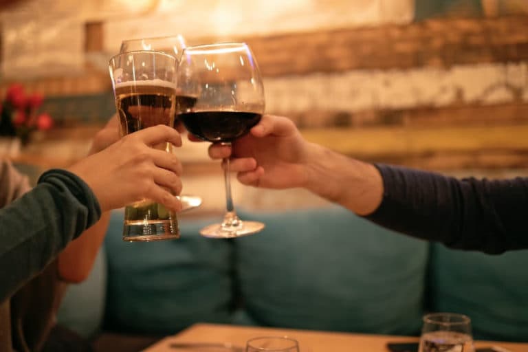 People toasting with glasses of beer and wine in a cozy setting.
