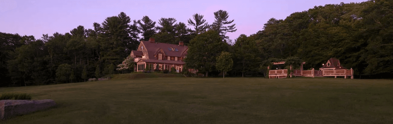 The Inn at Lake Joseph in Forestburgh, NY at dusk, with the pool and wooded Catskills grounds softly lit.