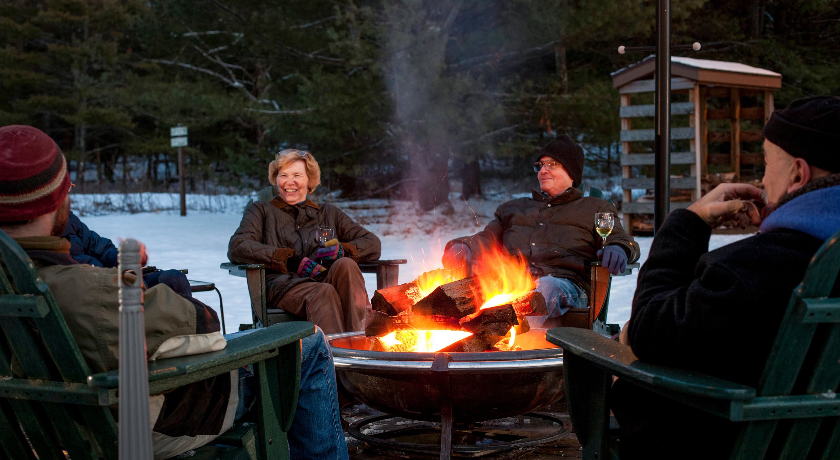 senior adults sitting outside in the dark and snow around a fire pit senior adults sitting outside in the dark and snow around a fire pit